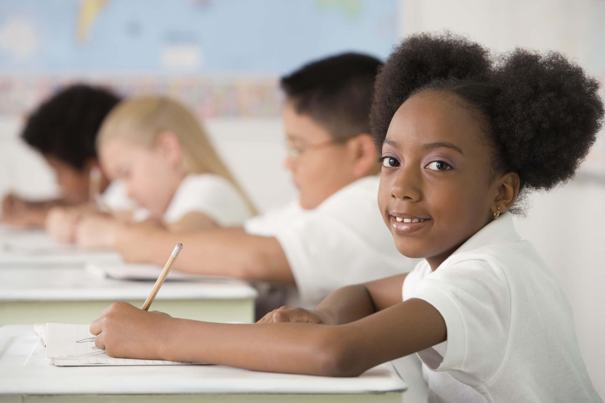 children writing at desks in a classroom